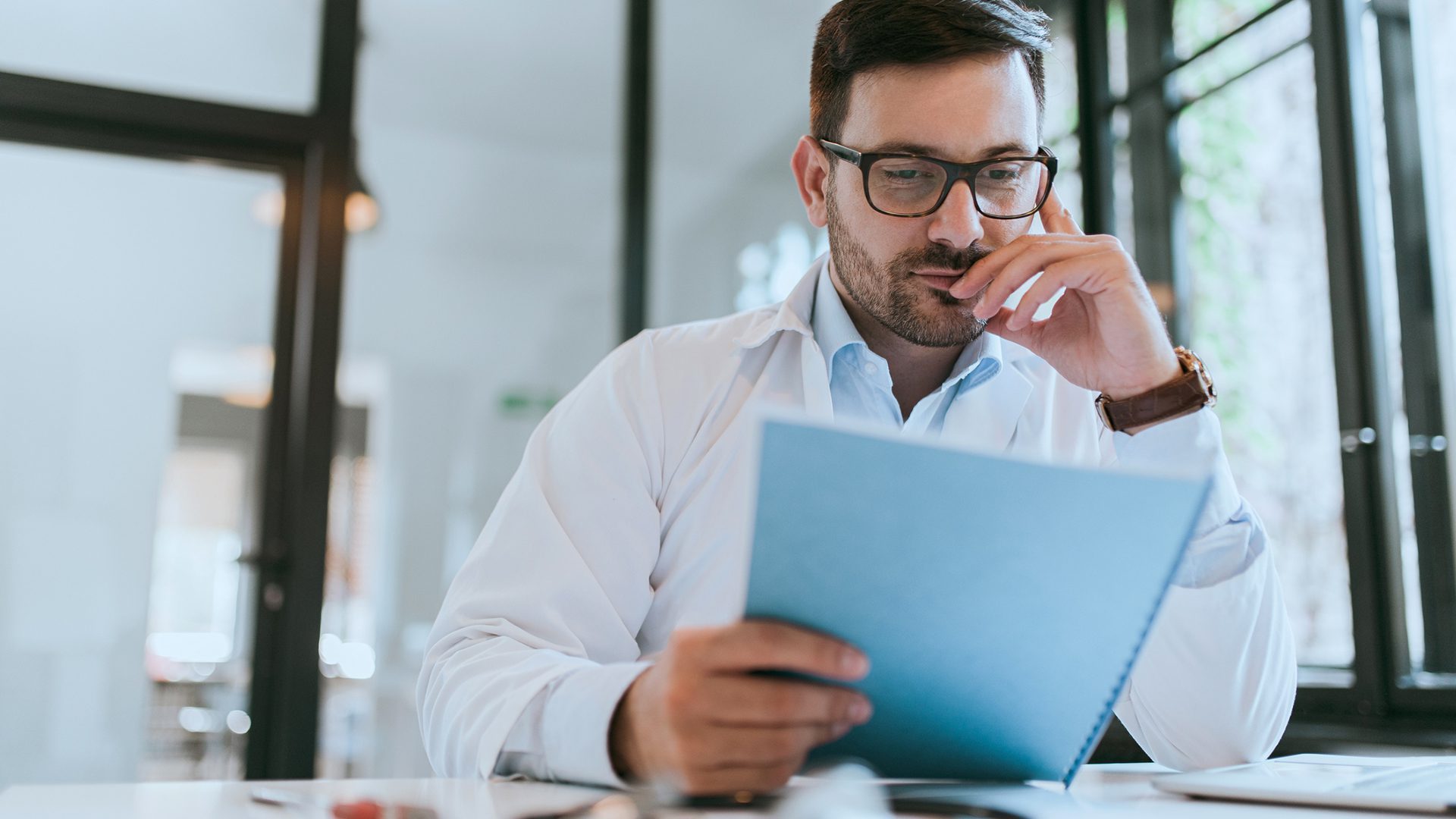 Portrait of a handsome doctor reading patients file, close-up.