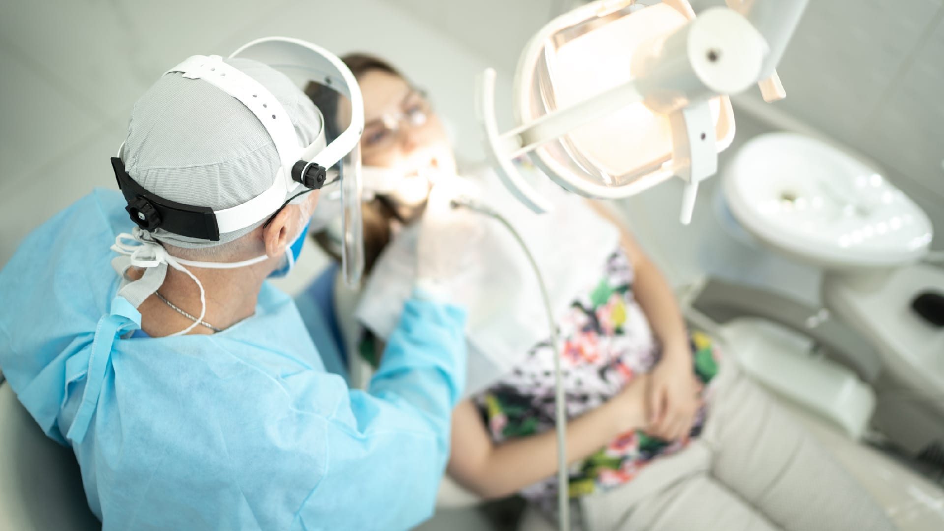 Senior dentist examining the teeth of a young woman