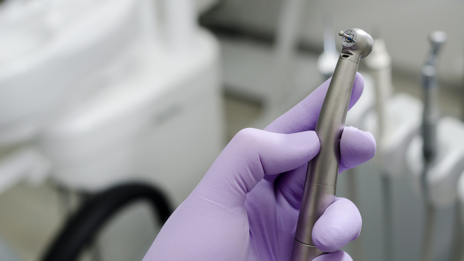 Hand of dentist holding dental drill machine with turbine