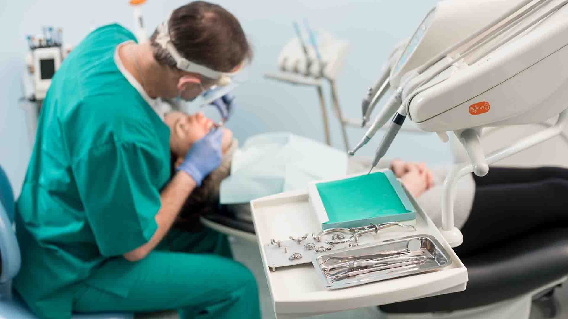 Different professional dental instruments, on the blurred background dentist is treating patient in dental clinic. Selective focus. Stomatology